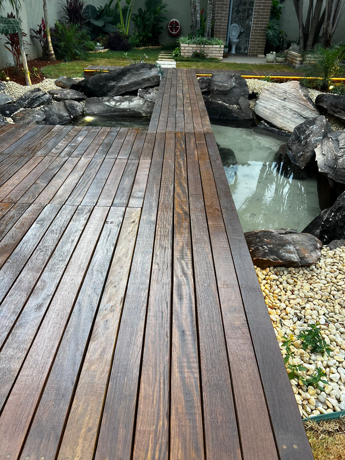 Deck de madeira com lago e pedras negras
